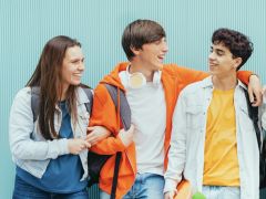 Diverse young people standing together in front of blue wall - Photo portrait of teenagers laughing together - Banner and 16:9 people background